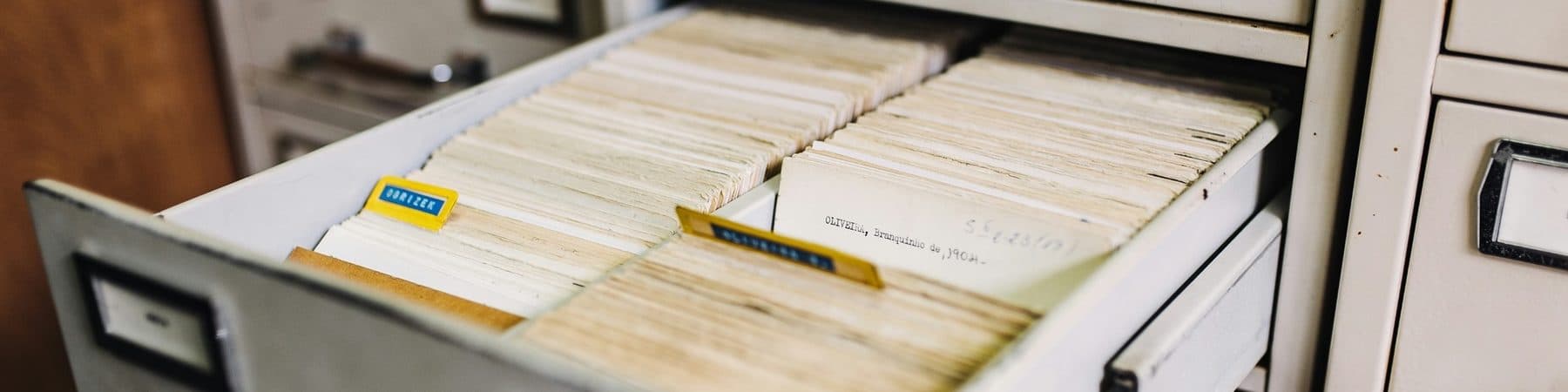 An open vintage filing cabinet drawer packed with index card records
